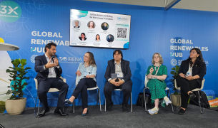 Two men in suits and three women in business clothing sit on a panel on a stage in front of a background that says Global Renewable Hub