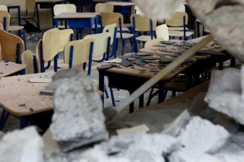 A classroom with rubble on the desks